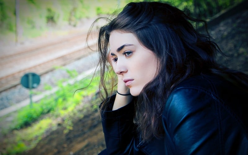 Sad woman sitting outdoors during daytime