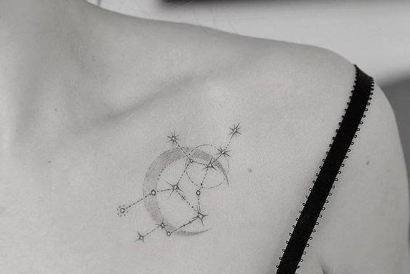 tatuagem da constelação de sagitário e do símbolo da lua no peito de uma mulher