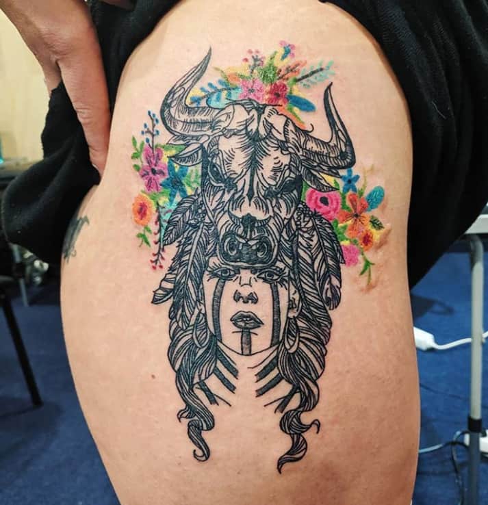 shaman girl with bull on her head tattoo surrounded with flowers