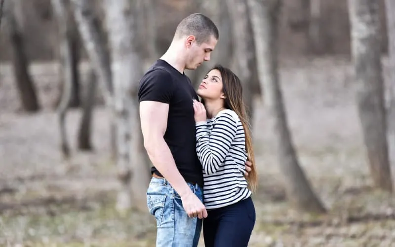 Short woman hugging tall man in a park during daytime