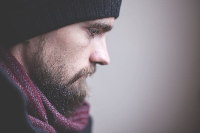 vista laterale di un uomo con barba e cappellino a fuoco