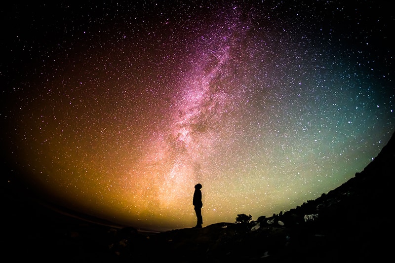 silhouette of person standing at night under the star sky