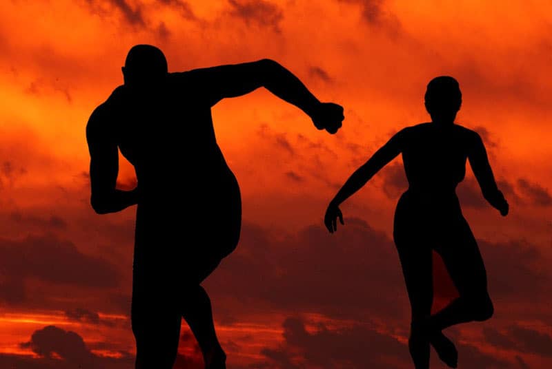 silhouette of two runners running with an orange skies background