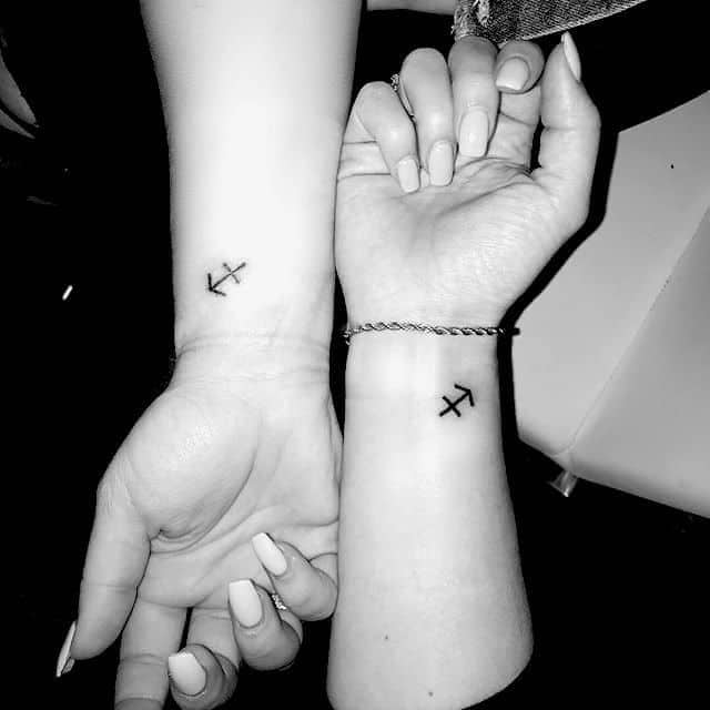 small sagittarius symbol tattoo on the two person`s wrist