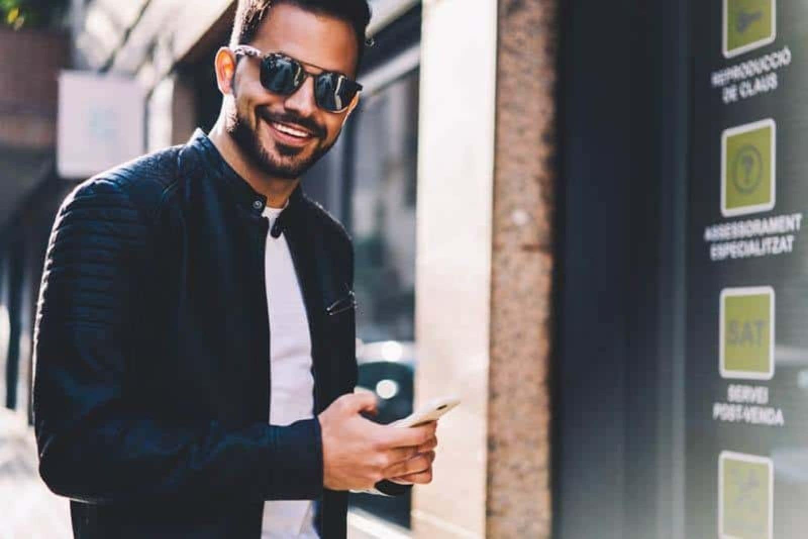 hombre sonriente sosteniendo su teléfono en el exterior