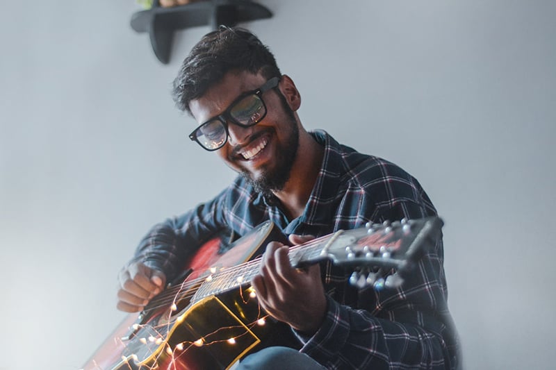 hombre sonriente sentado tocando la guitarra