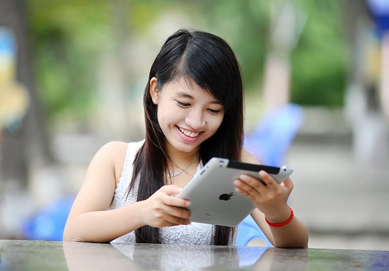 mujer sonriente con iPad al aire libre