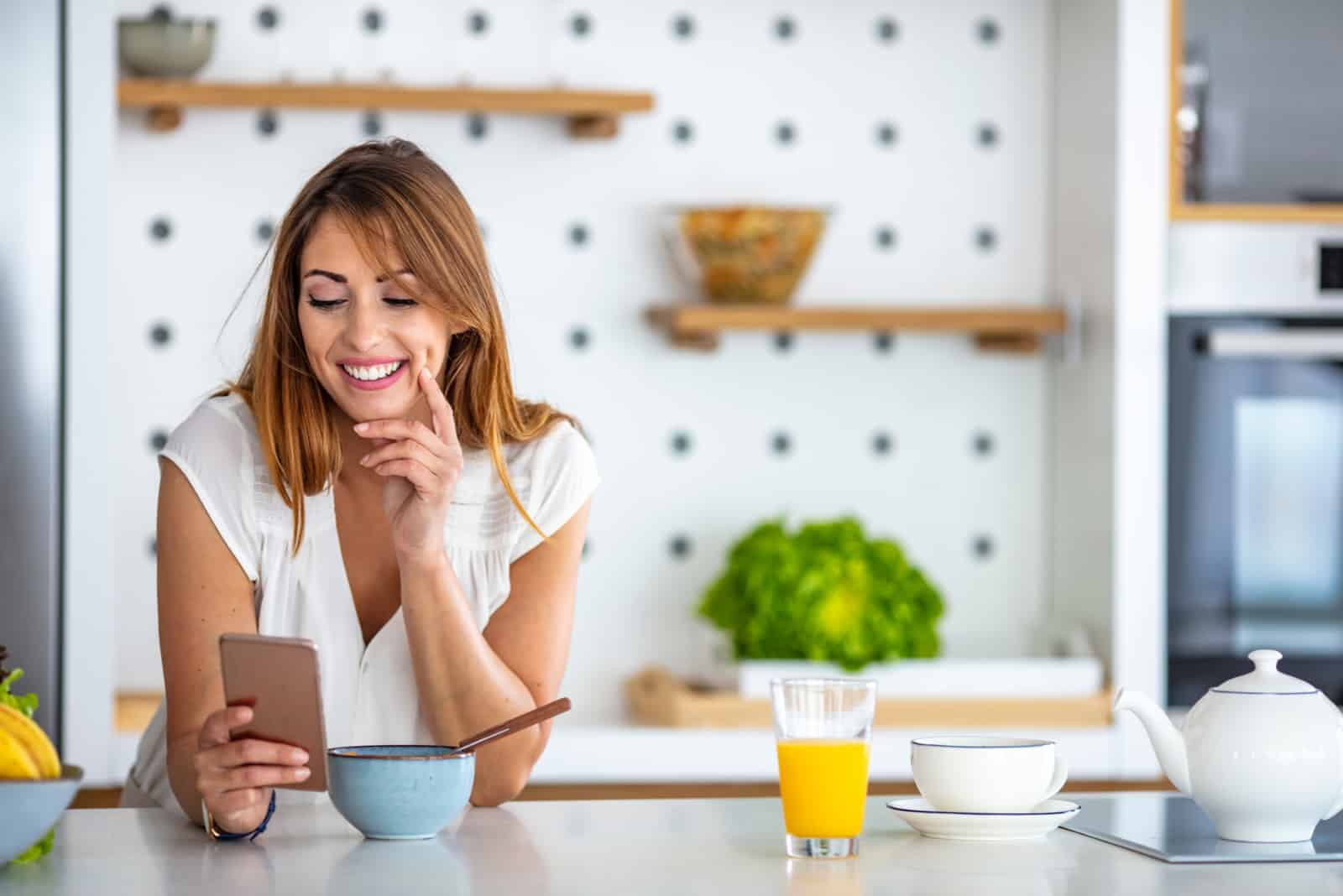 mujer sonriente en el botón de la cocina en el teléfono