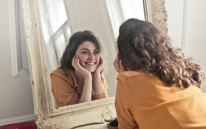 mujer sonriente mirándose al espejo