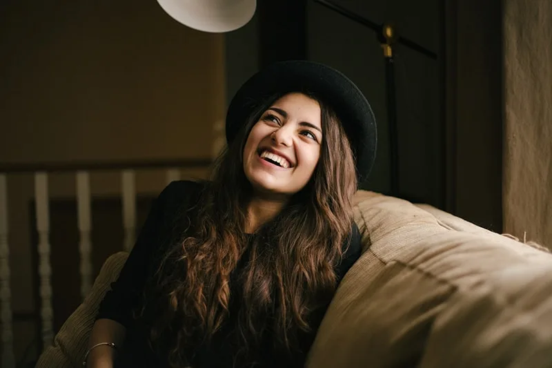 smiling woman wearing black hat sitting on the sofa