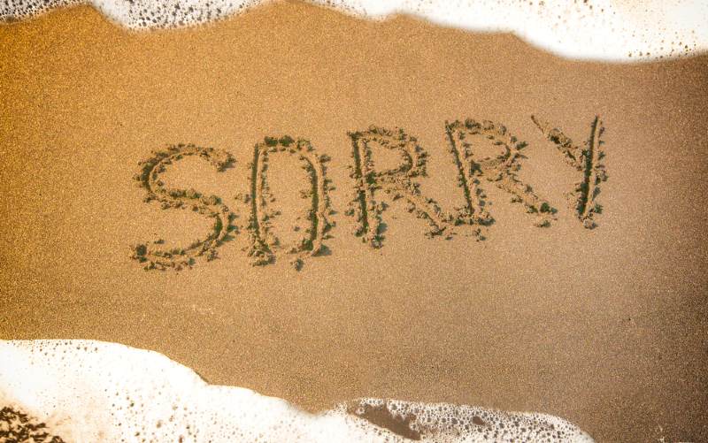 The word Sorry written on sea beach