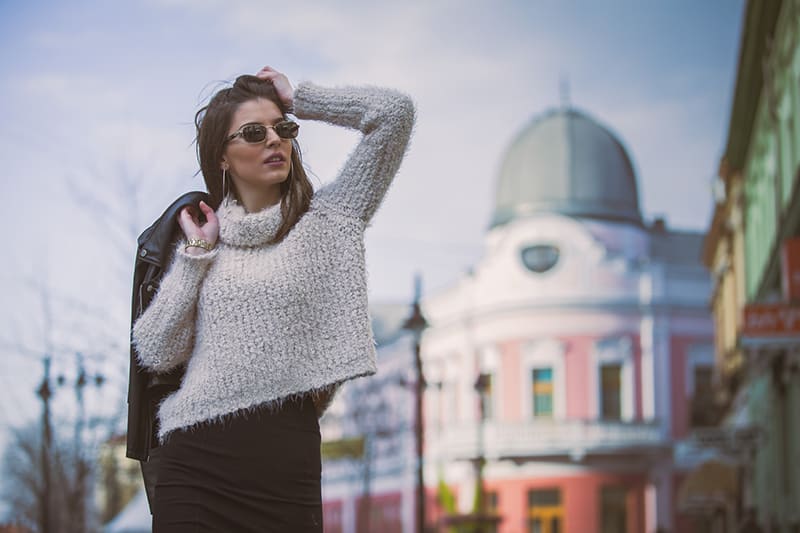 standing woman holding coat near buildings 