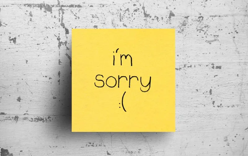 yello sticky note with I am sorry text on concrete wall