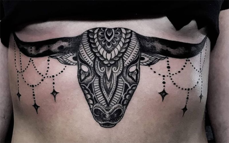 stylized bull`s head tattoo on the ribs