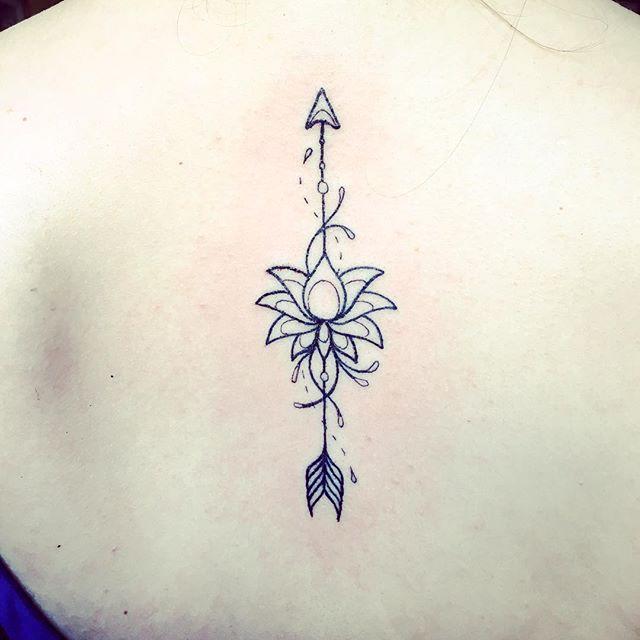 tatuagem de uma seta de lótus na linha da coluna vertebral