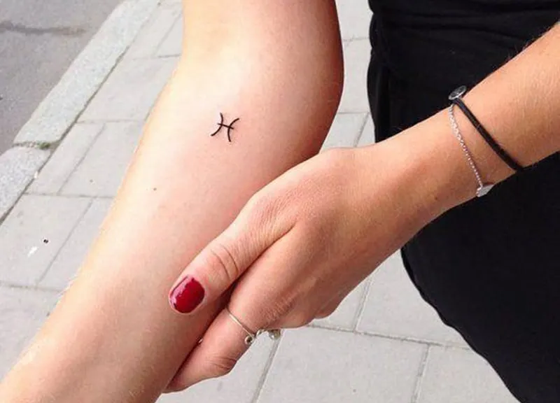 tattoo of pisces symbol on woman`s hand