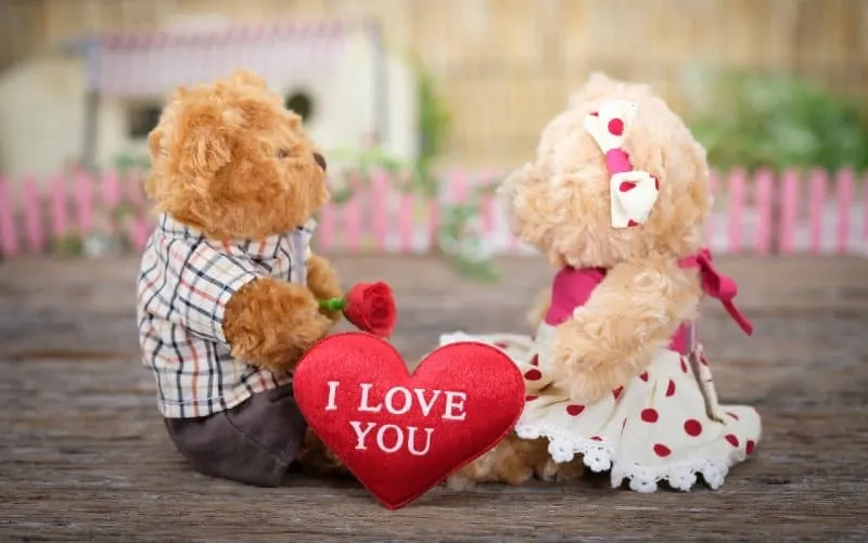 Teddy bears sitting on wood with I love you heart