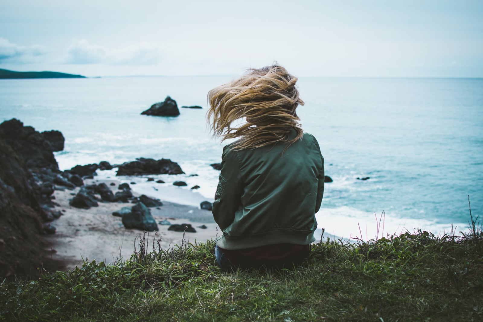 the woman is sitting on the grass with her back turned