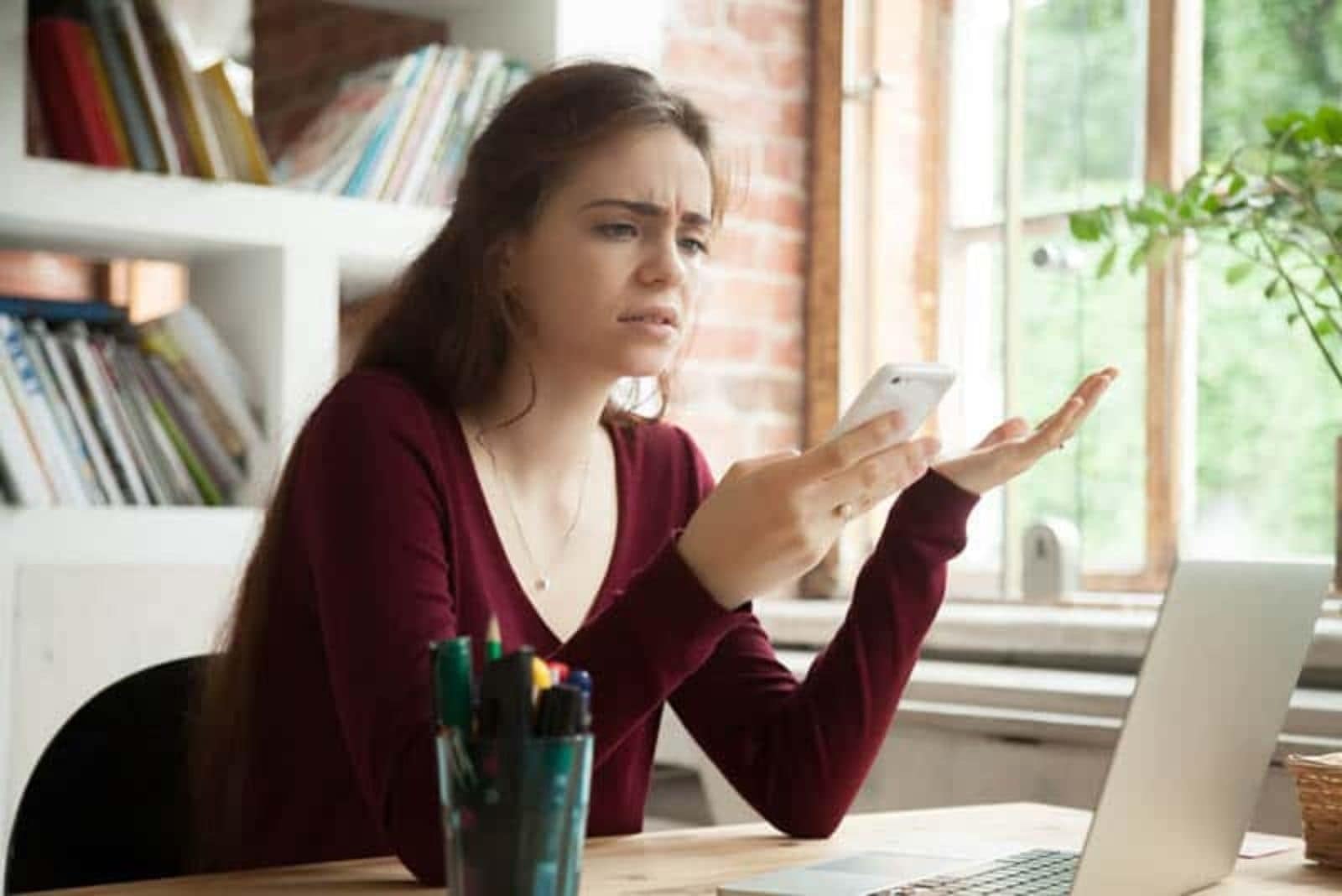 a mulher olha para o telemóvel com confusão