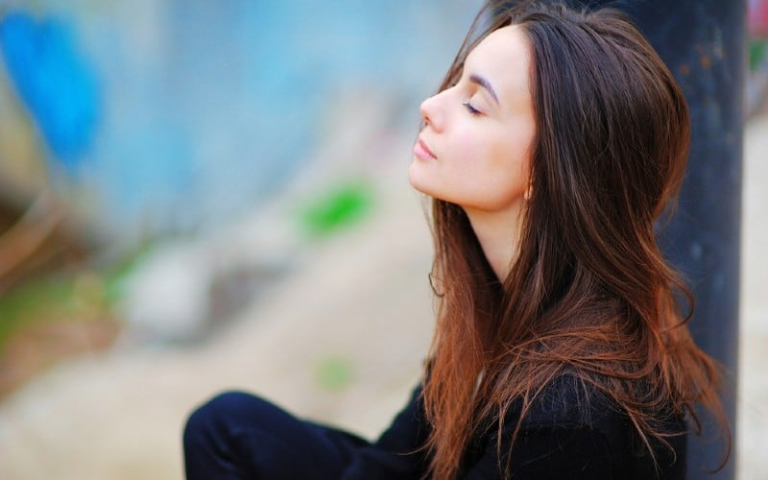 Happy thinking woman standing outdoors