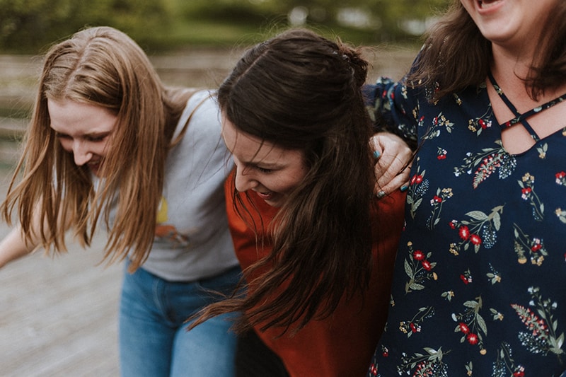 three women holding each other while laughing