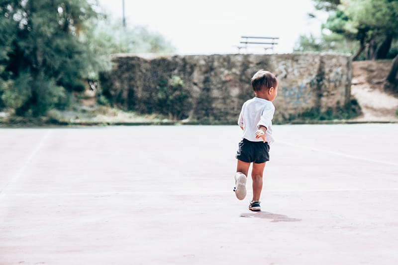 niño corriendo sobre suelo de cemento gris