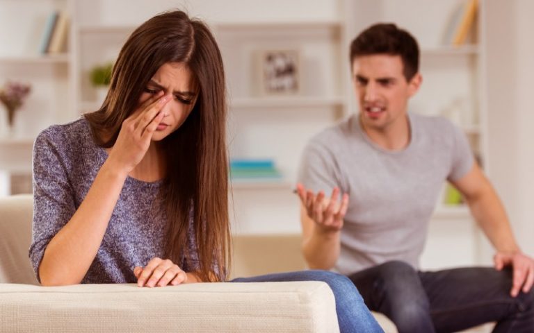 Crying woman sitting nest to angry man on a couch