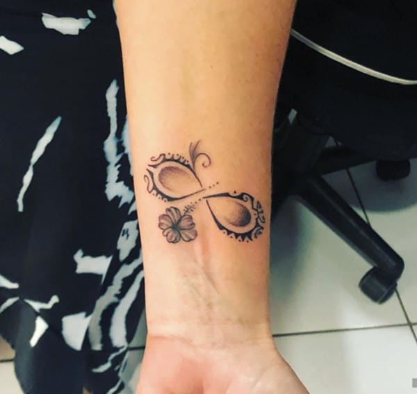 disegno del tatuaggio tribale con fiore e piccoli punti sul polso