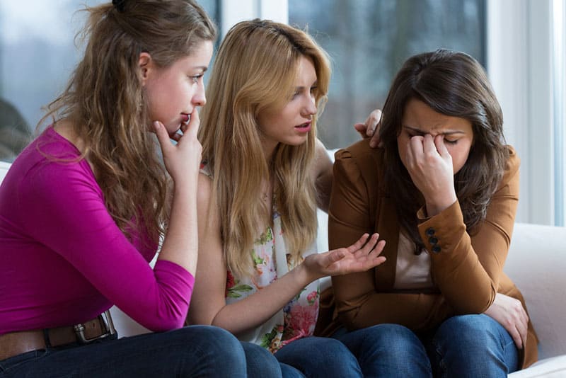 two friends comforting sad woman