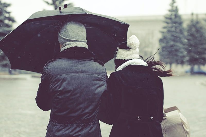  due persone sotto l'ombrello in una giornata di neve