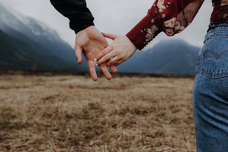 two persons holding hands in the field