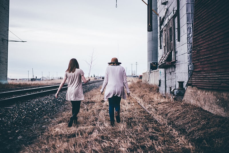  two persons walking along railway near old building