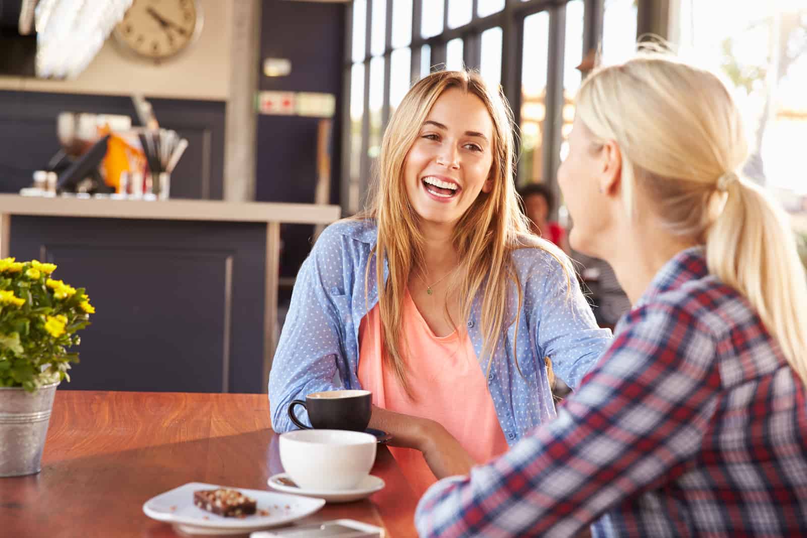 dos amigos sonrientes se sientan a charlar tomando un café