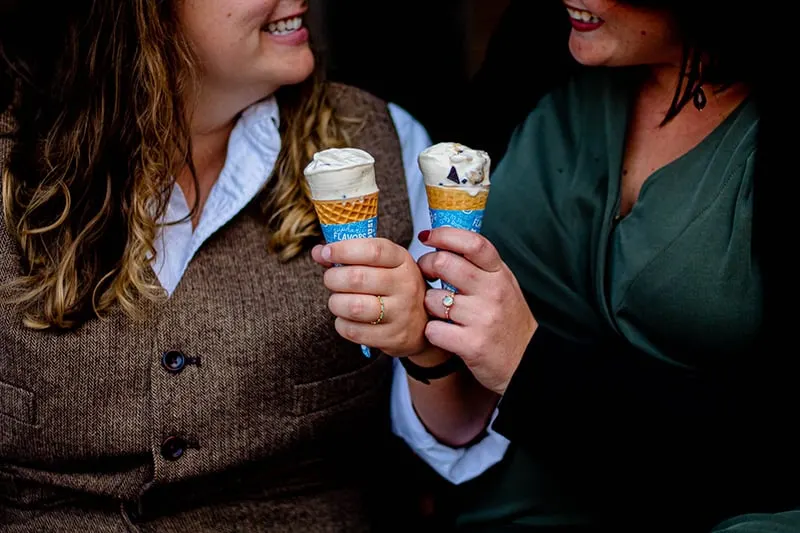 two smiling women holding ice cream in cones