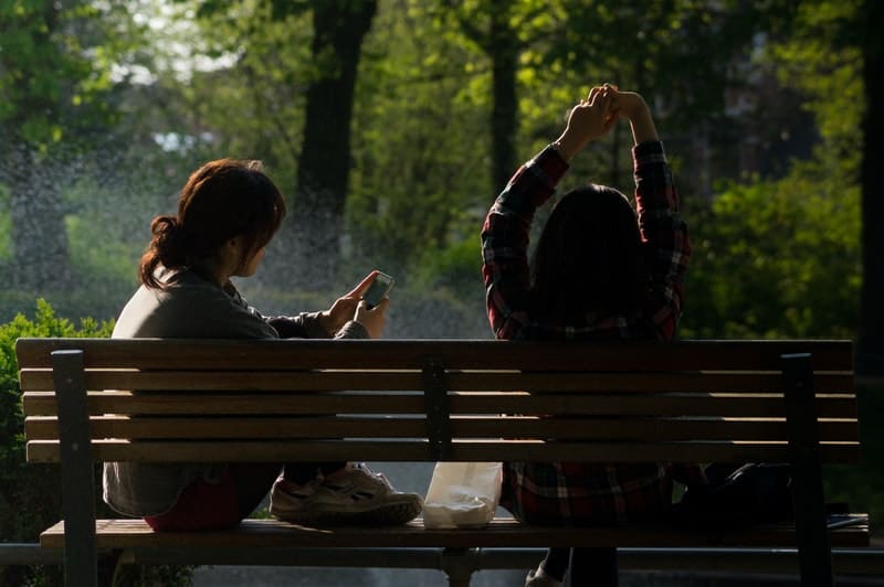 due donne sulla panchina che si rilassano con una donna al telefono cellulare