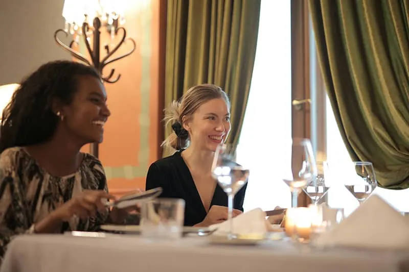 two women sitting by the table while having a lunch
