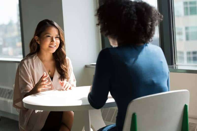 dos mujeres sentadas en una silla conversan