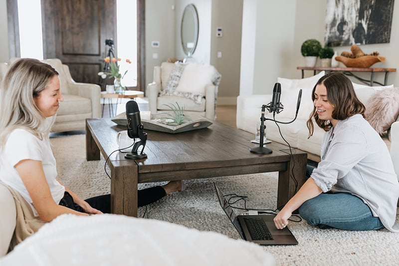 two women sitting on the floor while using laptop computer