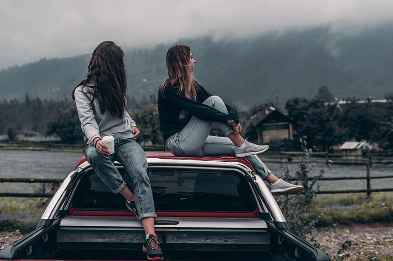 due donne sedute sul tetto del veicolo vicino al lago