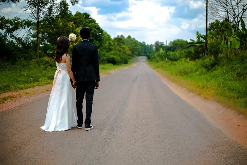 wedding couple standing on the road between trees