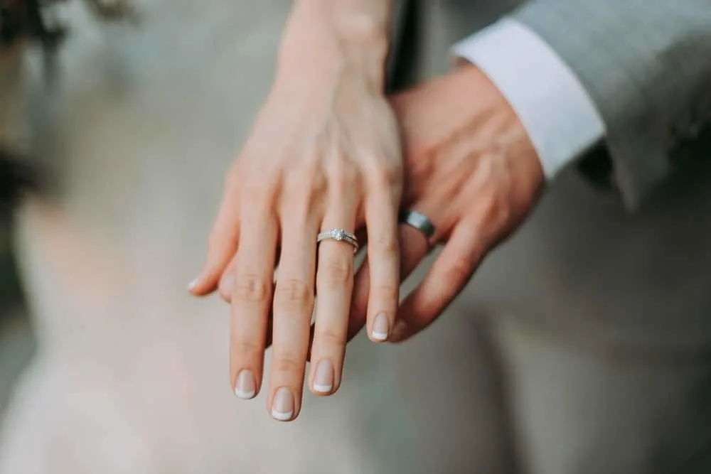 woman touch man's hand wedding ring