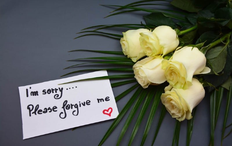 White roses and note with please forgive me written on it