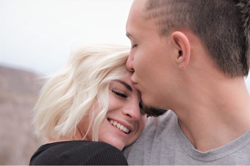 Man kissing happy blonde woman on her forhead