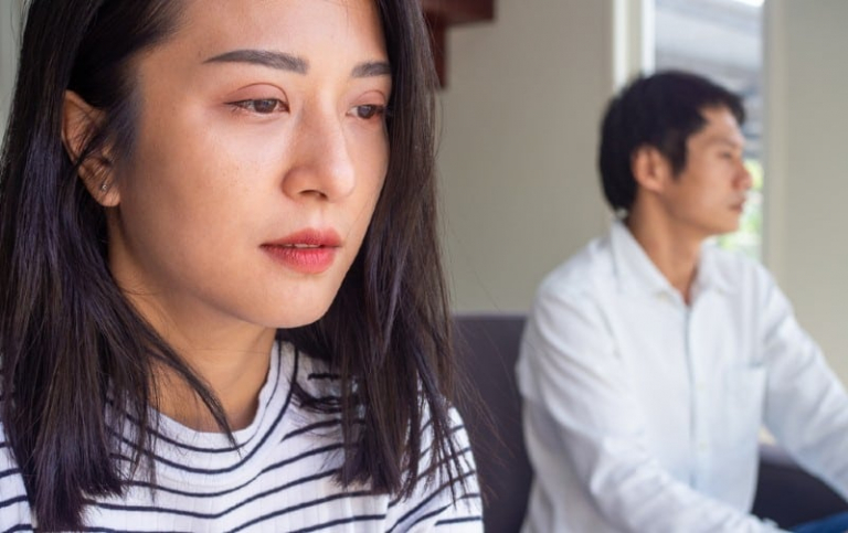 Sad woman crying stitng near man