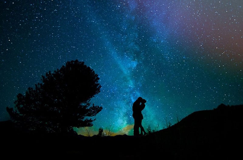 woman and man embracing under a beautiful dark bluish purple sky