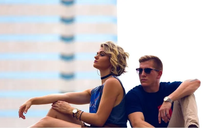 Woman and man sitting back to back by a window