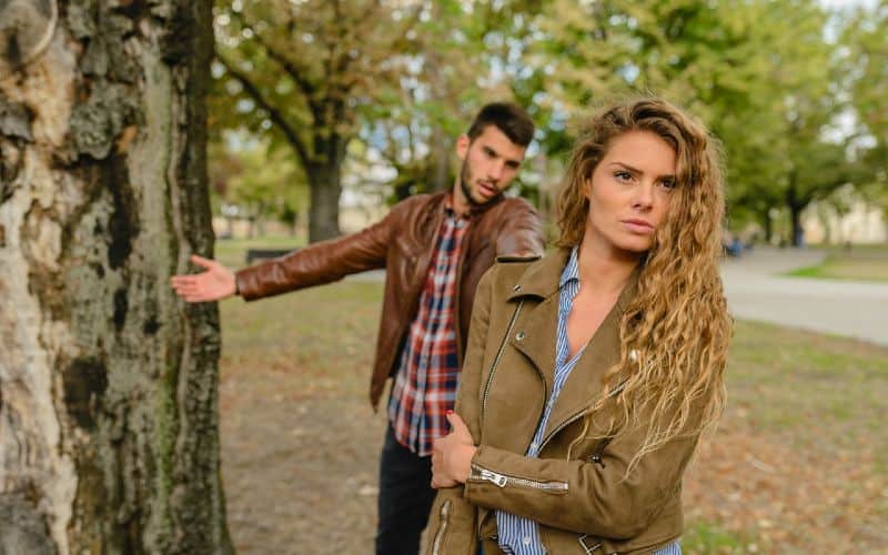 woman and man wearing brown jackets standing near tree during daytime