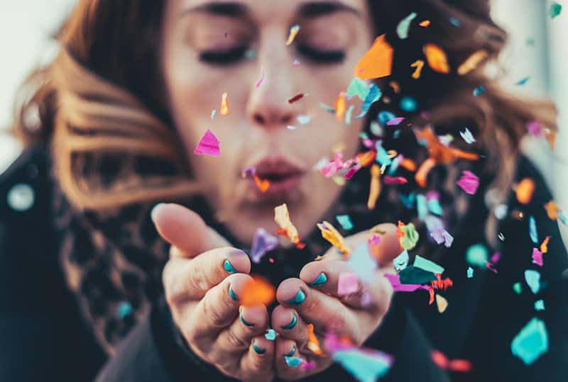 woman blowing paper strips from her palms