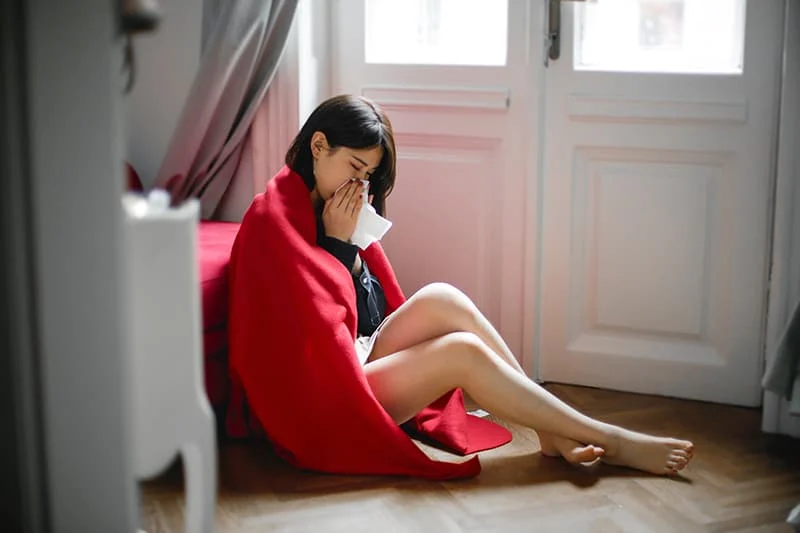 woman covered with red blancket sitting on the floor