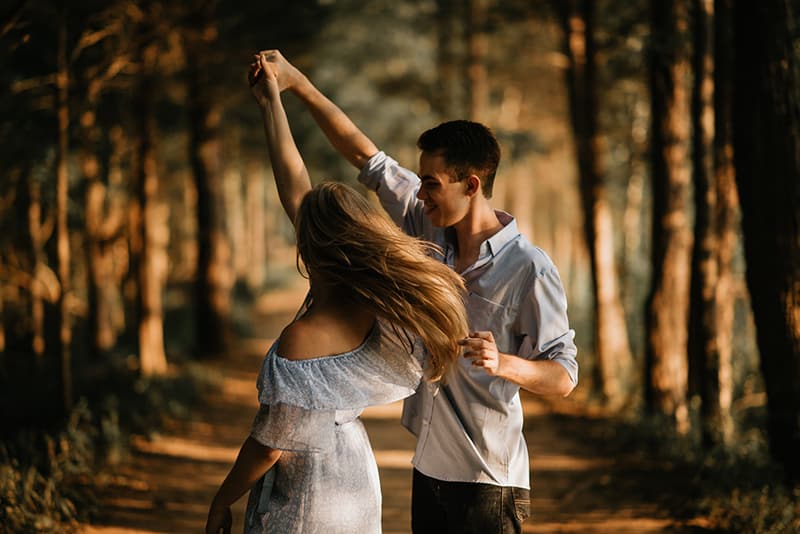 donna che balla con un uomo circondato da alberi